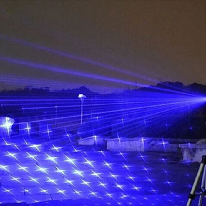 Blauer Laserprojektor im Freien, strahlende Lichtmuster, Nachtaufnahme, Partybeleuchtung.
