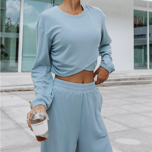 Frau in hellblauem Trainingsanzug mit Eiskaffee, sportliche Freizeitkleidung, draußen.