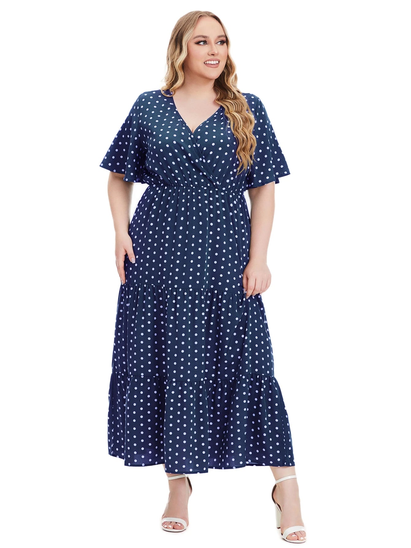 Frau im blauen gepunkteten Maxikleid, V-Ausschnitt, Plus-Size, Sommermode, weiße Sandalen.
