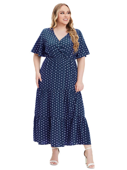 Frau im blauen gepunkteten Maxikleid, V-Ausschnitt, Plus-Size, Sommermode, weiße Sandalen.