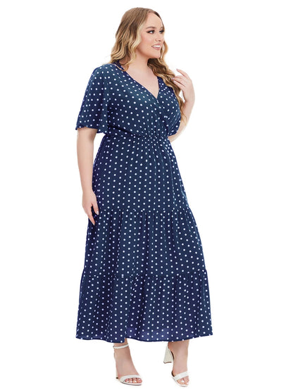 Frau im blauen Maxikleid mit weißen Punkten, V-Ausschnitt, Plus-Size, Sommermode.