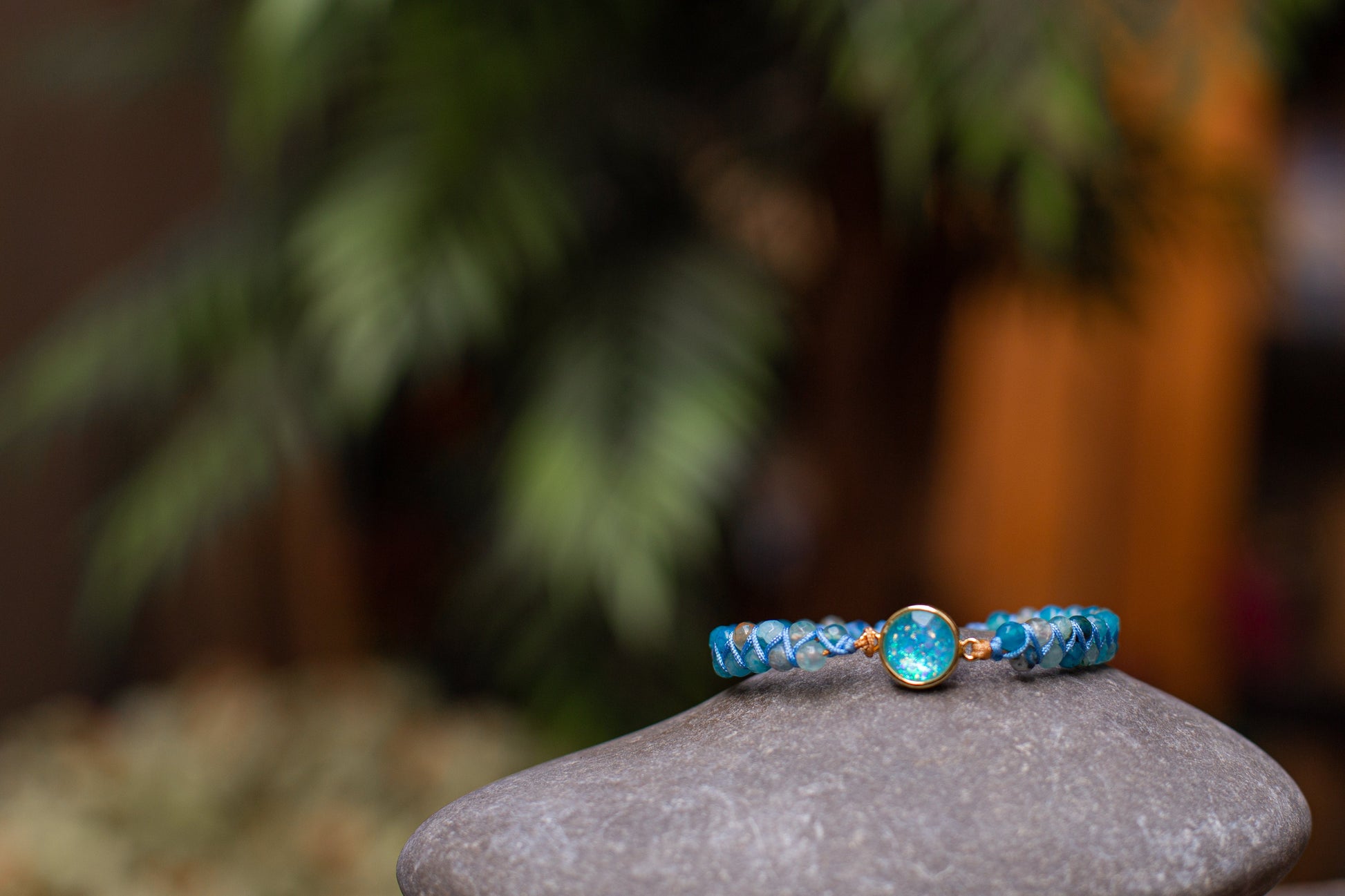 Blaues Armband mit Edelstein auf grauem Stein, Naturhintergrund, Schmuckfotografie.