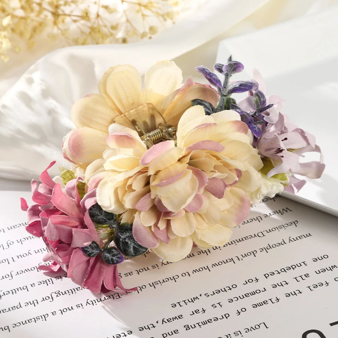 Seidenblumen-Haarklammer, cremefarben, rosa und lila, auf Buchseite liegend.
