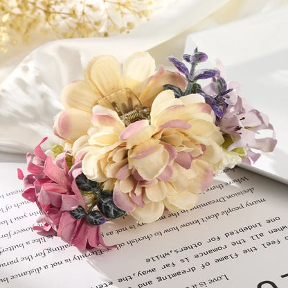 Seidenblumen-Haarklammer, cremefarben, rosa und lila, auf Buchseite liegend.