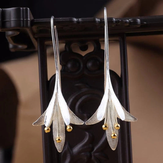 Silberne Blumenohrringe mit goldenen Akzenten, eleganter Schmuck für Frauen, festlich.