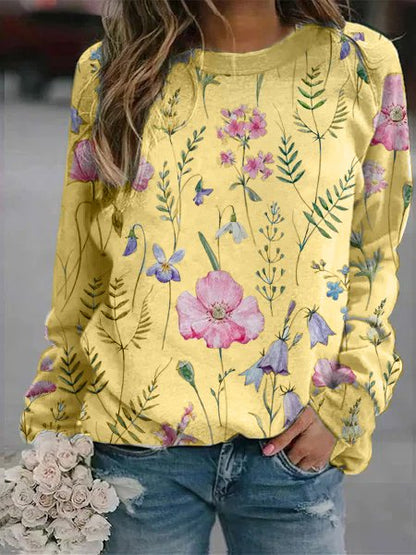 Frau in gelbem Blumenpullover, Jeans, hält weißen Blumenstrauß, modisch, lässig.