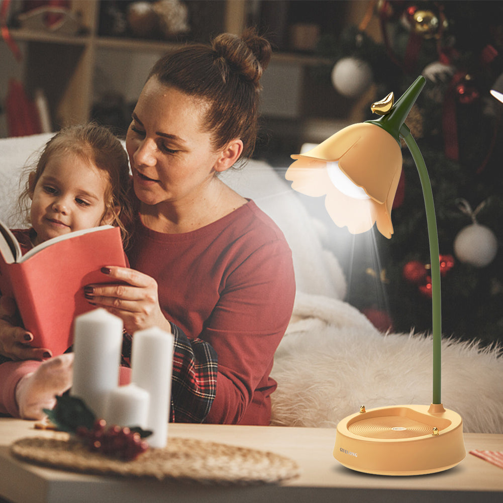 Frau liest Kind Buch vor, beleuchtet von gelber Blütenlampe, gemütliches Wohnzimmer, Weihnachtsdeko.