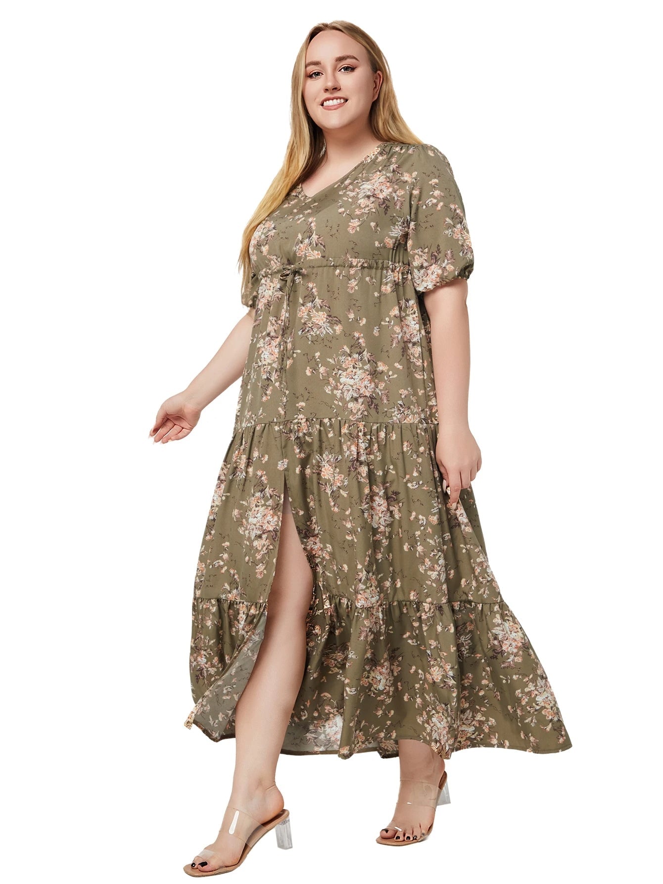 Frau im langen, grünen, geblümten Kleid mit V-Ausschnitt und transparenten Absatzschuhen.