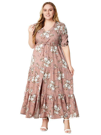 Frau in rosa, geblümtem Maxikleid mit V-Ausschnitt und kurzen Ärmeln, lächelnd, weiße Sandalen.