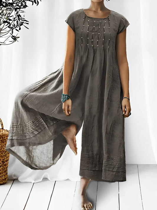 Frau trägt grauen Boho-Jumpsuit aus Leinen, modisch, ärmellos, Sommermode, elegant.