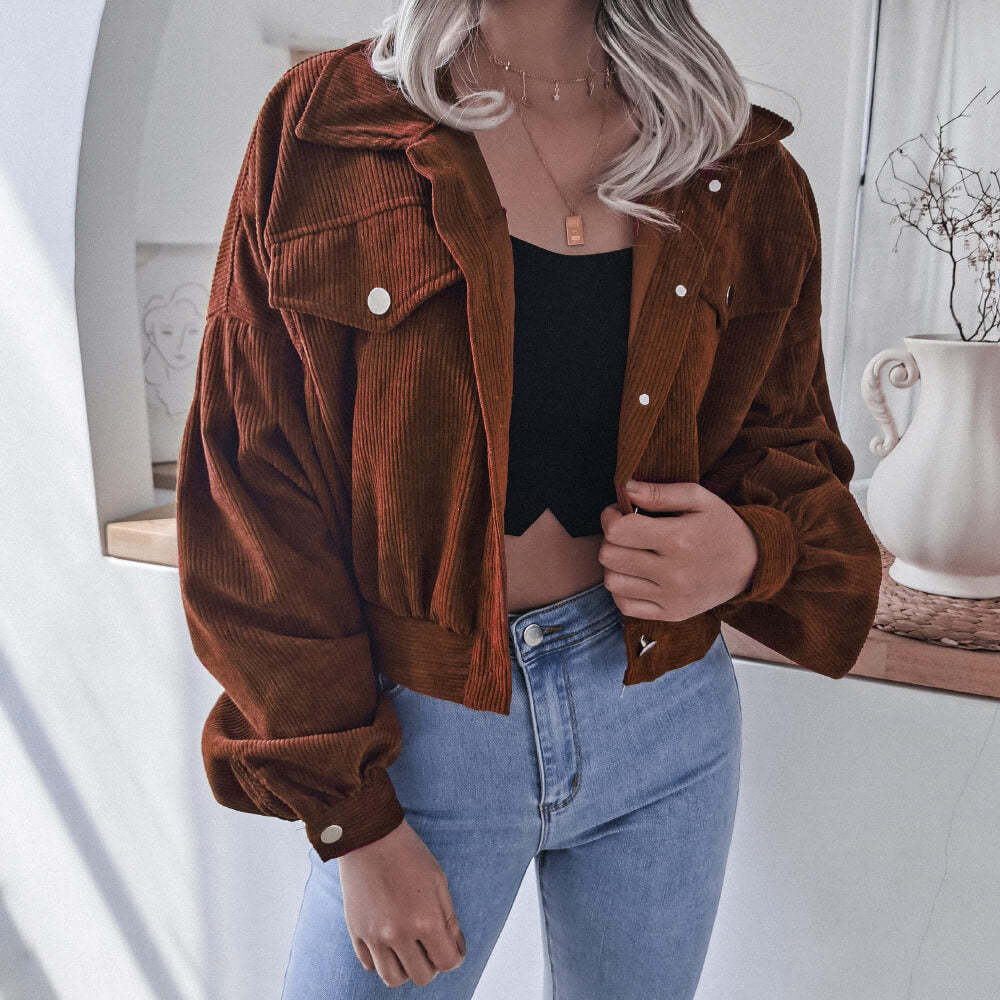 Frau in brauner Cordjacke, schwarzem Top und blauer Jeans, modisch, lässig, Herbstoutfit.