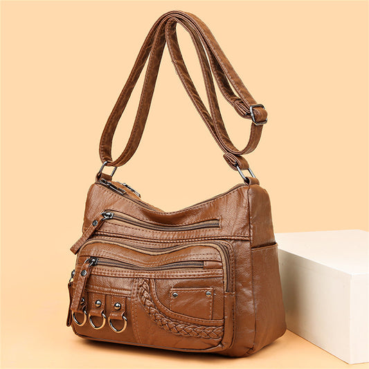 Braune Lederhandtasche mit mehreren Reißverschlusstaschen und verstellbarem Schulterriemen.