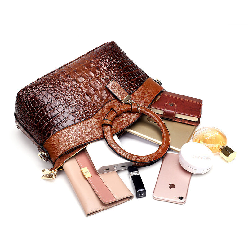 Luxuriöse braune Krokodilleder-Handtasche mit Accessoires, Smartphone und Kosmetik.
