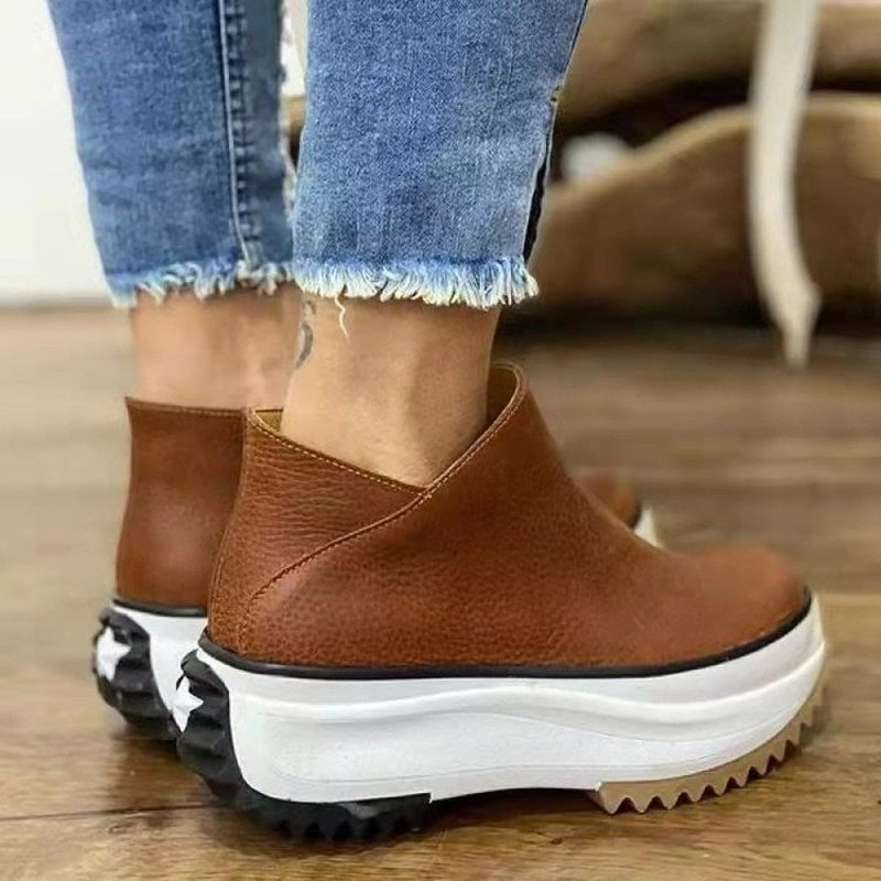 Braune Lederstiefeletten mit Plateau, Damenmode, lässig, robuste Sohle, Jeanshintergrund.