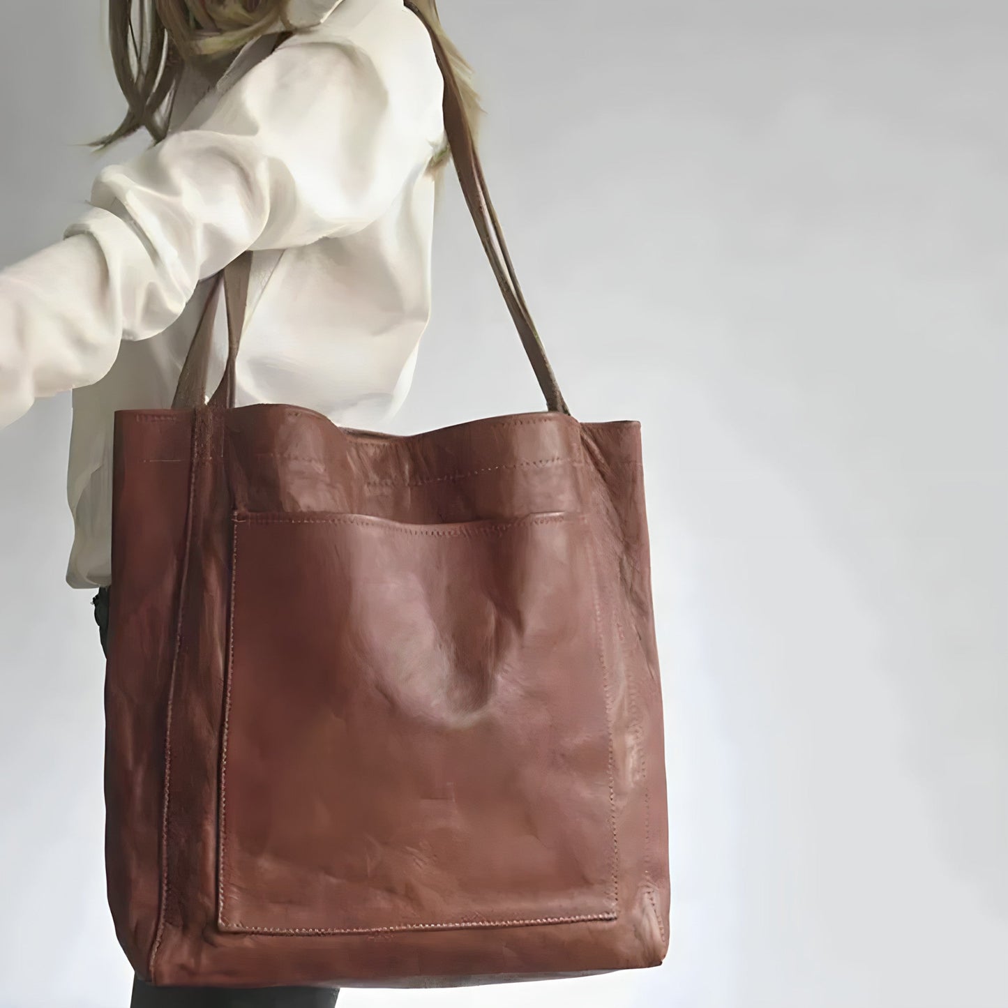 Frau mit großer brauner Ledertasche, modisches Accessoire, elegantes Design.
