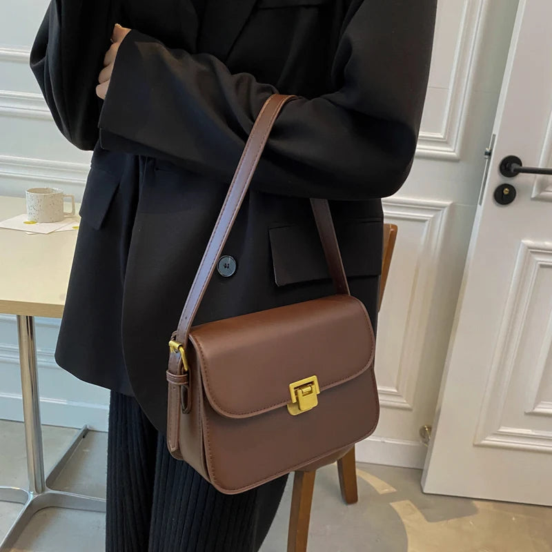 Braune Lederhandtasche mit goldener Schnalle, elegant, Damenmode, Accessoire, modern.