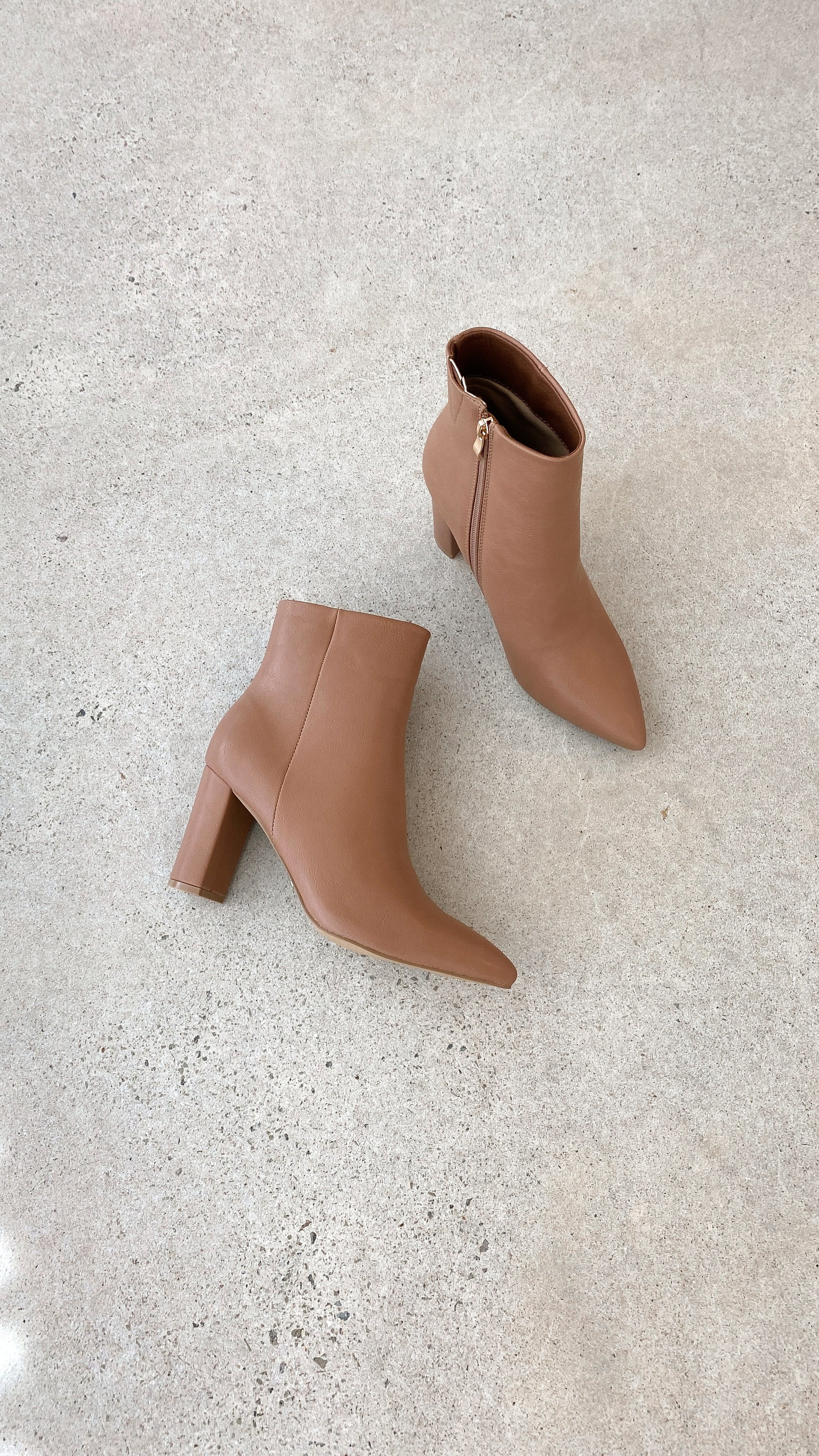 Braune Damen-Stiefeletten mit Blockabsatz, Reißverschluss, Lederoptik, auf Betonboden.