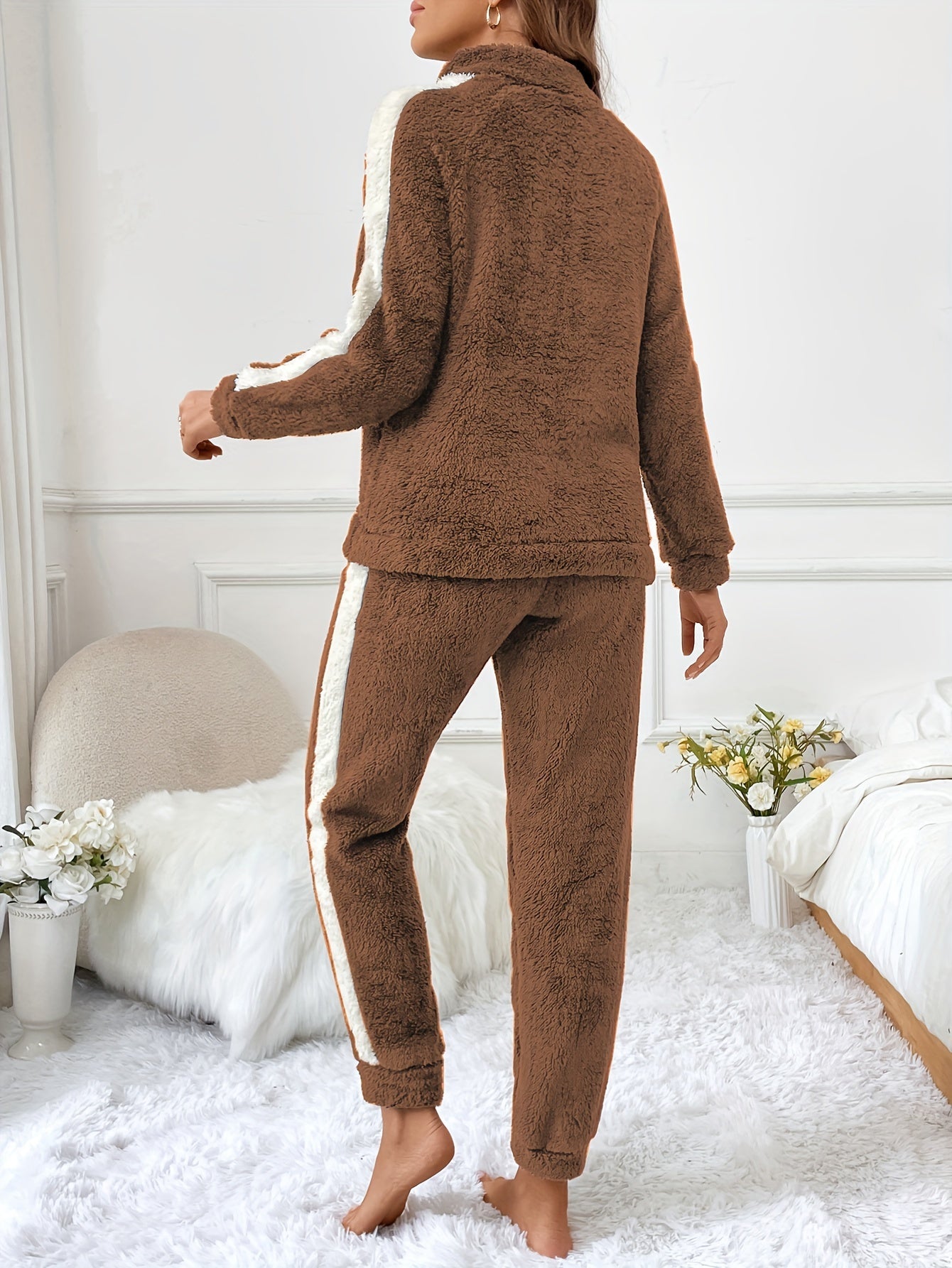 Frau in braunem Fleece-Trainingsanzug, gemütlich, modisch, Wohnzimmer, Blumen, weißer Hintergrund.