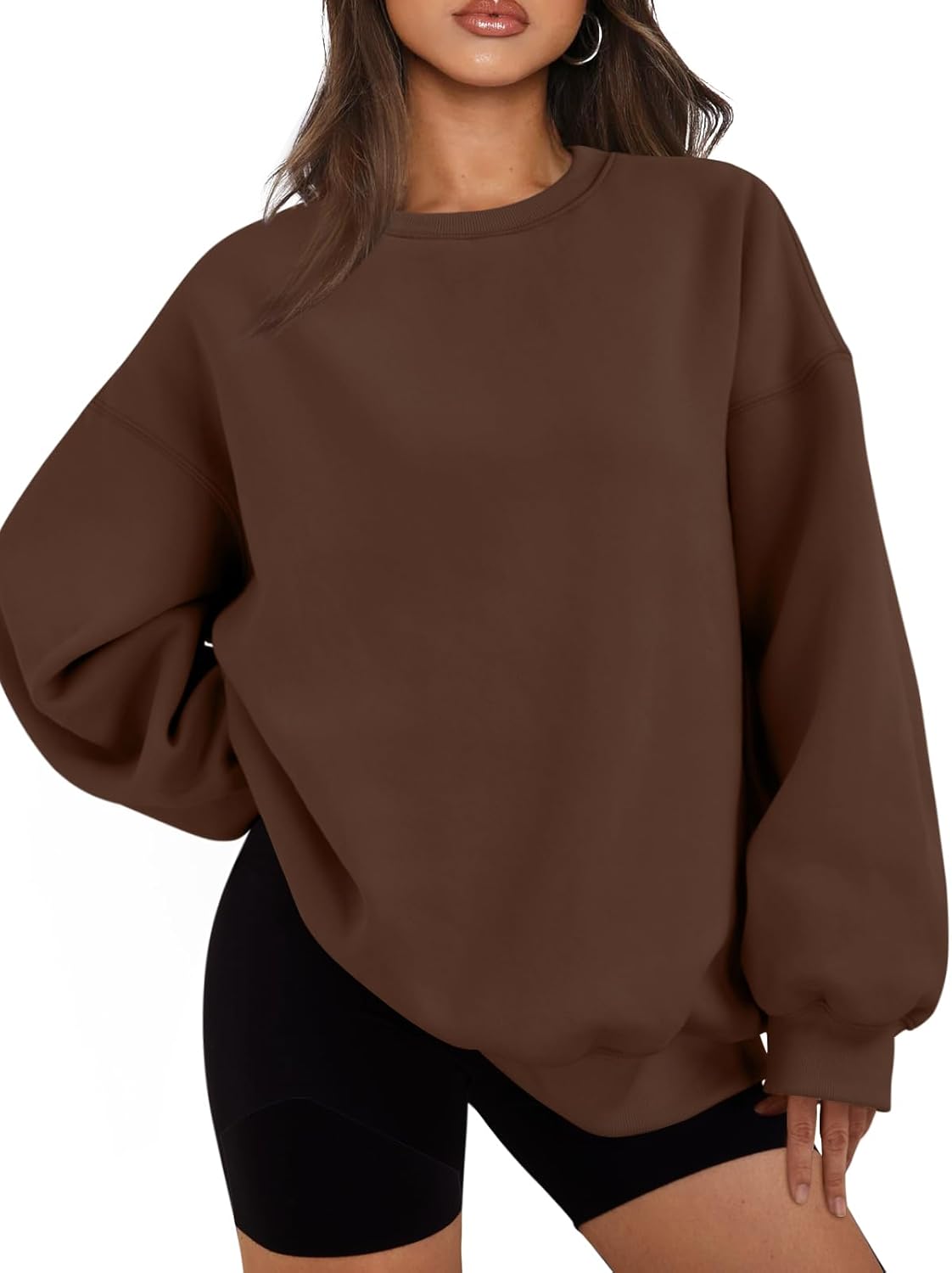 Frau in braunem Oversize-Pullover und schwarzen Shorts, modisch, lässig, Herbstmode.