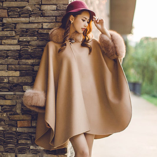 Frau in beigem Wollponcho mit Kunstpelz, rotem Hut, Herbstmode, stilvoll, elegant.