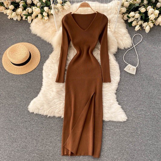 Braunes Strickkleid mit V-Ausschnitt, Langarm, Schlitz, auf weißem Fellteppich, elegantes Design.