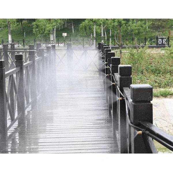 Holzbrücke mit Sprühnebelanlage im Park, schwarze Geländer, grüne Umgebung, Sommertag.