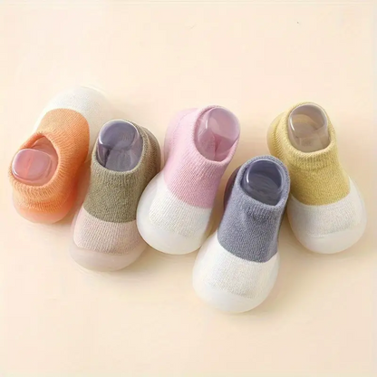 Fünf Paar bunte Babysocken aus Baumwolle, rutschfest, für Neugeborene, auf beigem Hintergrund.