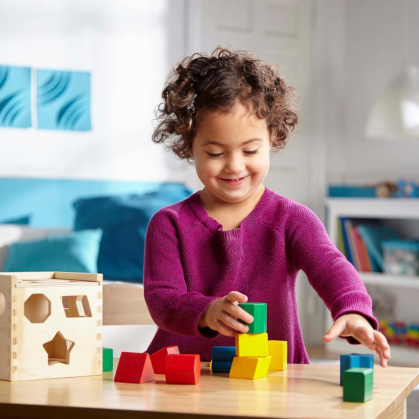 Kleinkind spielt mit bunten Holzbausteinen und Sortierbox im Kinderzimmer.