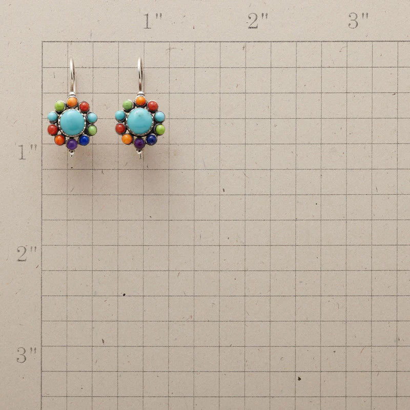 Bunte Ohrringe mit Türkis und bunten Perlen auf kariertem Hintergrund, handgefertigter Schmuck.