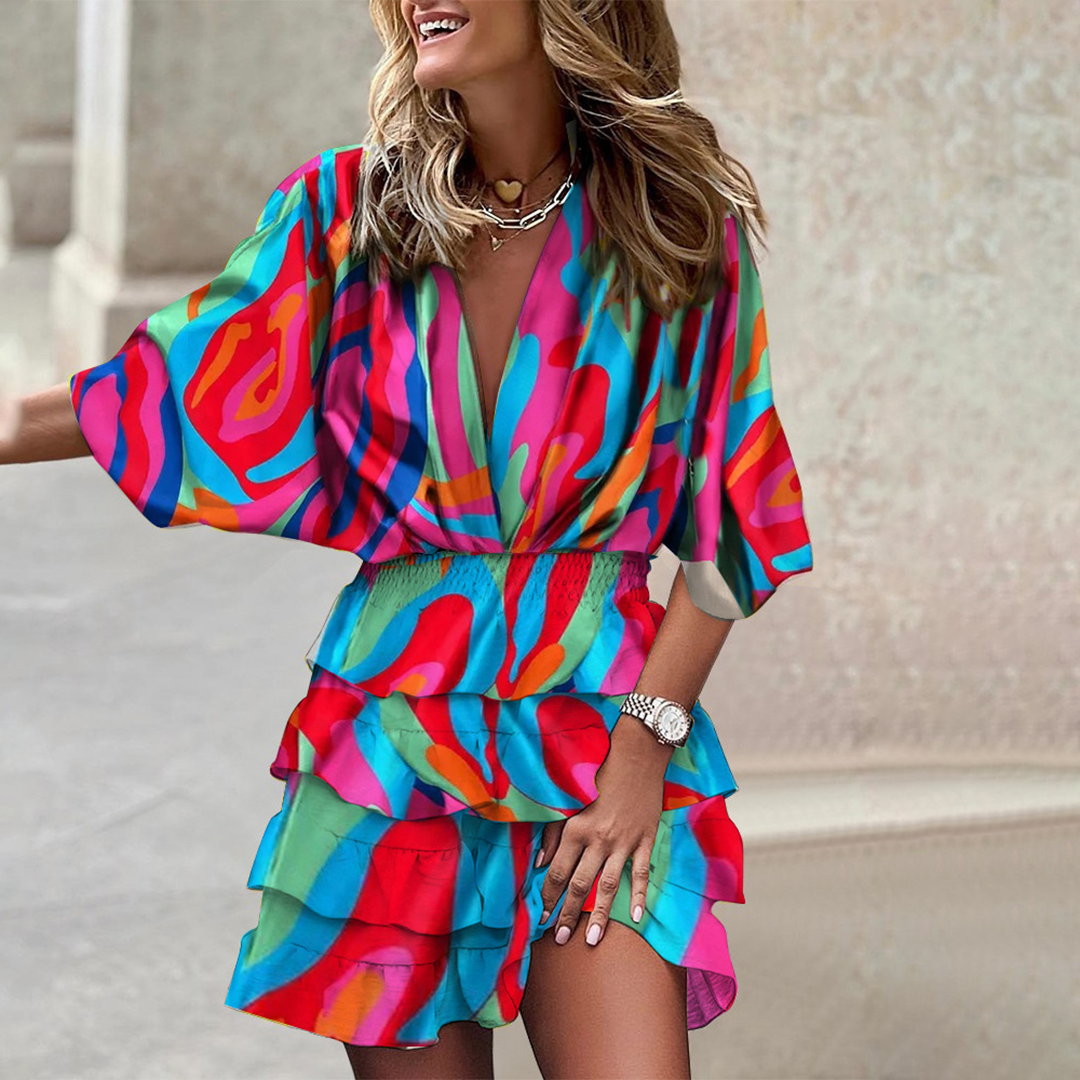 Frau in buntem, gemustertem Sommerkleid mit Rüschen, lächelnd, modisch, draußen.