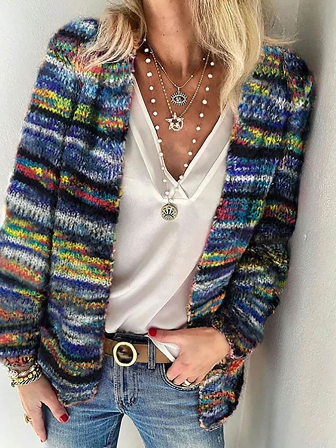 Frau mit bunter Strickjacke, weißem Top, Jeans und Schmuck, modischer Freizeitlook.