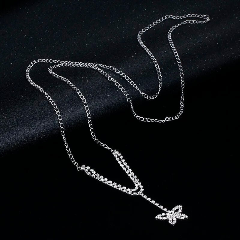 Silberne Schmetterlingskette mit Kristallen auf schwarzem Hintergrund, eleganter Schmuck.