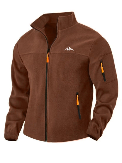 Braune Fleecejacke von vorn mit offenem Stehkragen, orangen Reißverschlussziehern, Ärmeltasche und kleinem Bergmotiv auf der 1