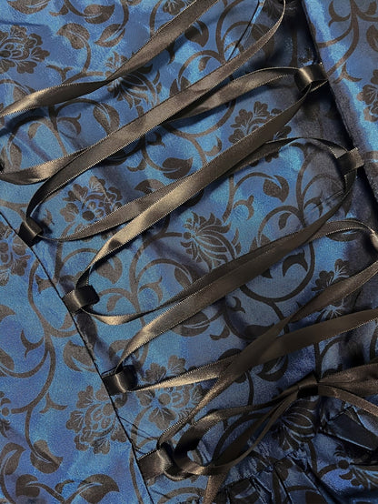 Detailaufnahme der schwarzen Satinband-Schnürung auf dem blauen Stoff mit schwarzem Blumenranken-Muster. 5