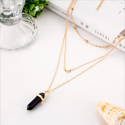 Goldene Halskette mit schwarzem Kristallanhänger auf weißem Hintergrund, Schmuck, Modeaccessoire.