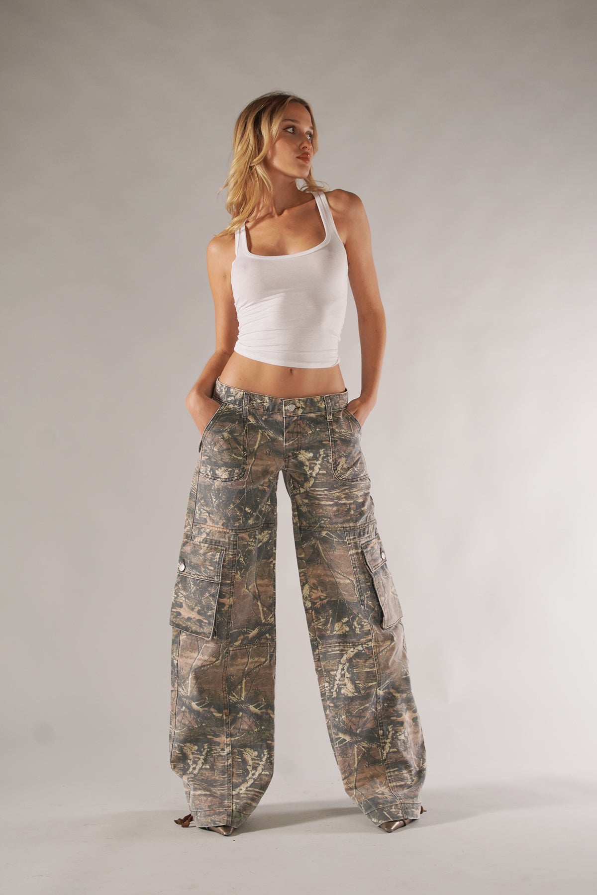 Frau in weißem Tanktop und Camouflage-Cargohose, Mode, lässiger Stil, Studioaufnahme.