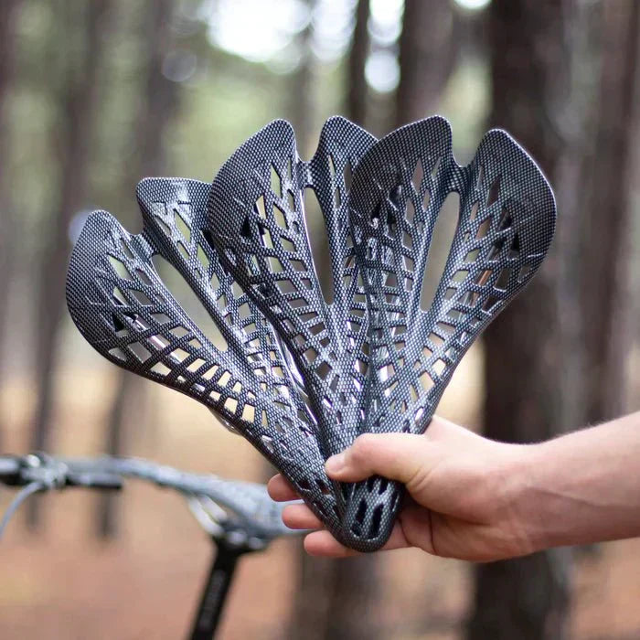 Hand hält Carbon-Fahrradsattel, leicht, ergonomisch, schwarz, ideal für Mountainbikes.