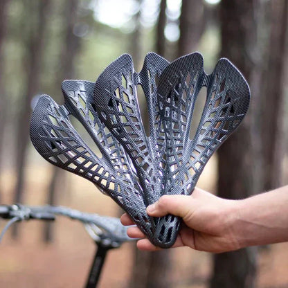 Hand hält Carbon-Fahrradsattel, leicht, ergonomisch, schwarz, ideal für Mountainbikes.