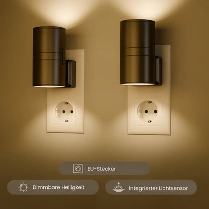 Zwei dunkle zylindrische Steckdosenleuchten an Wandsteckdosen werfen warmes Licht nach oben und unten, mit Funktionssymbolen 1