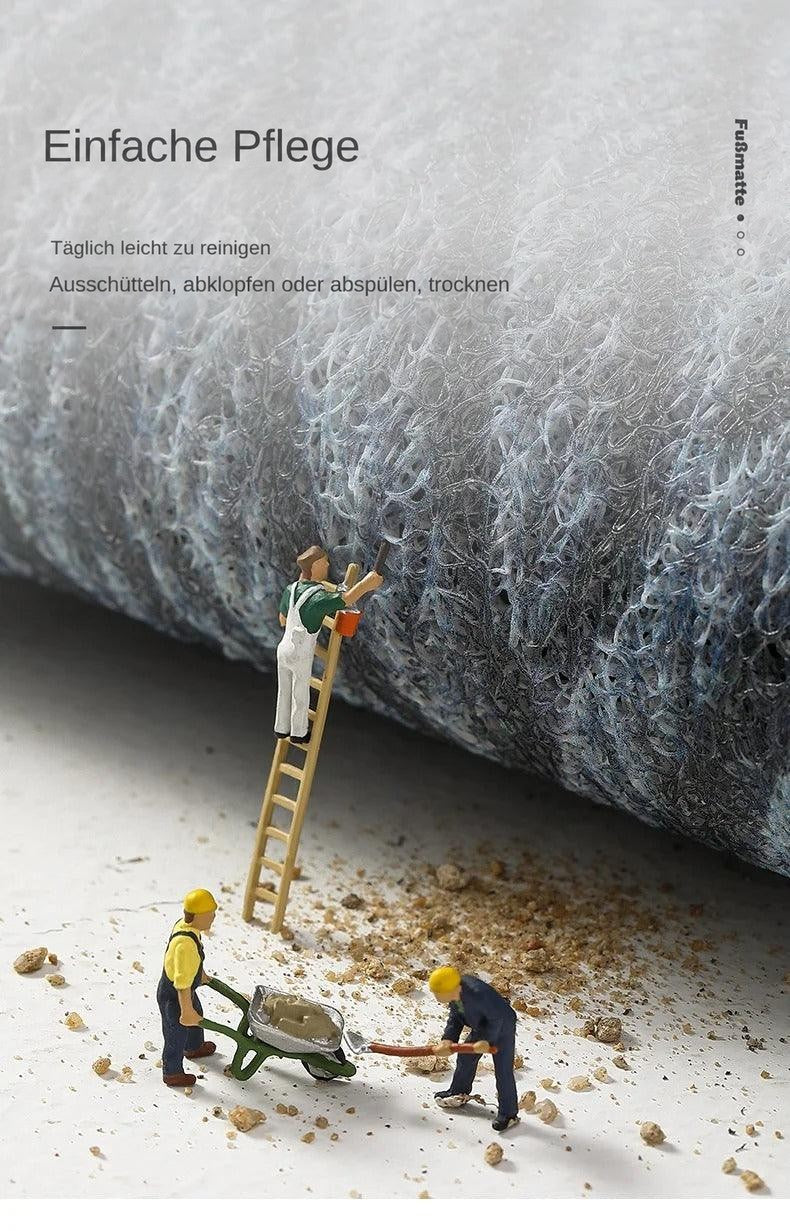 Nahaufnahme der weichen, schlingenartigen Mattenoberfläche, auf der Miniaturarbeiter Sand abtragen 12