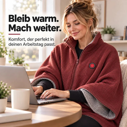 Frau arbeitet am Laptop an einem Holztisch, eingehüllt in die rote Heizdecke mit grauem Futter 11