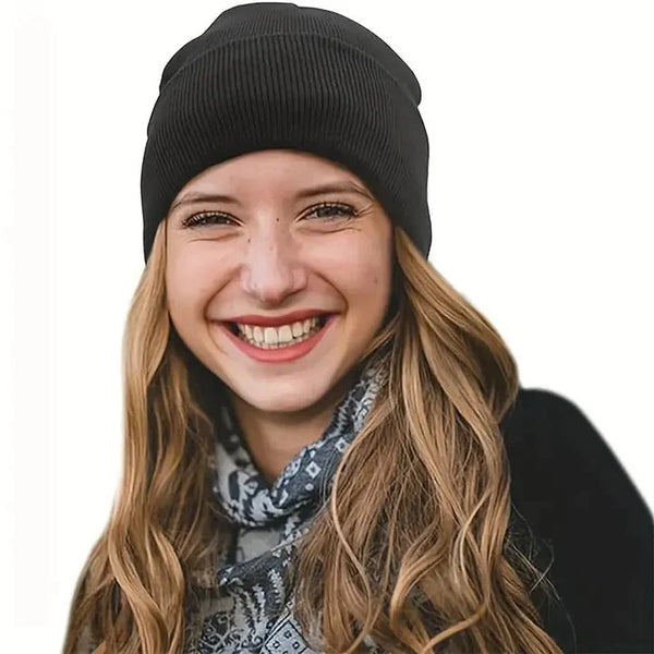 Lächelnde Frau mit langen welligen Haaren trägt eine schwarze Strickmütze und einen gemusterten Schal 3