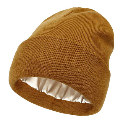 Senfgelbe Strickmütze mit Umschlag, innen mit glänzendem cremefarbenem Satinfutter, einzeln freigestellt 1
