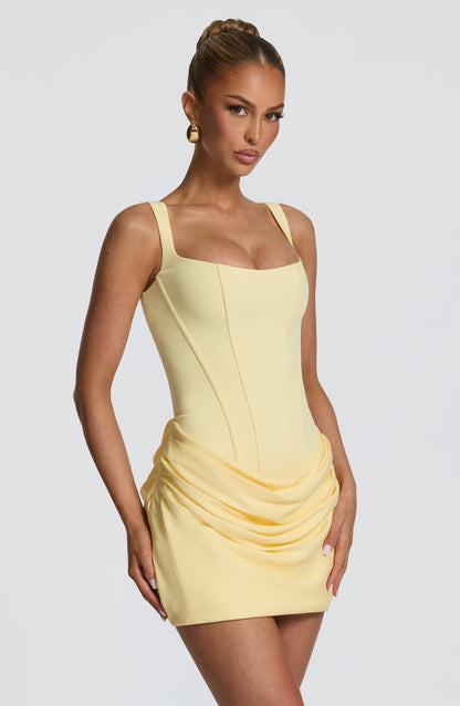 Gelbes Minikleid in Dreiviertelansicht am Model, Korsagennähte und fließende Raffungen an der Hüfte gut sichtbar. 24
