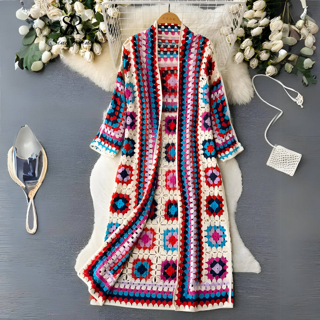 Bunter gehäkelter Cardigan mit geometrischem Muster, umgeben von Blumen und Accessoires.