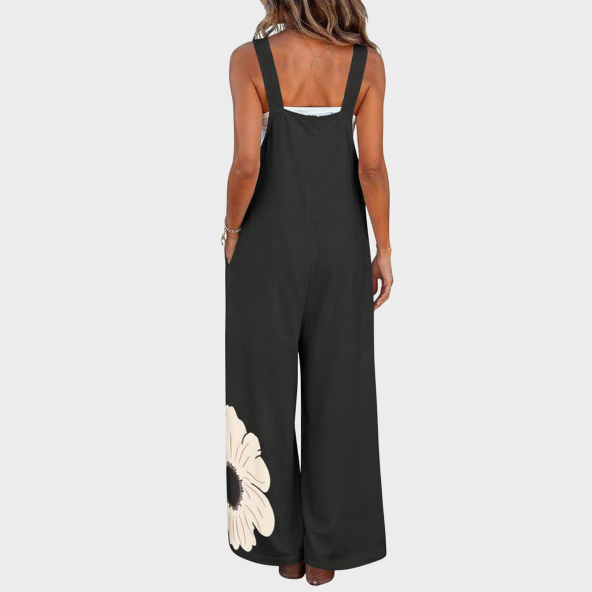 Rückansicht der schwarzen Latzhose mit breiten Trägern und cremefarbener Blüte am unteren Hosenbein 3