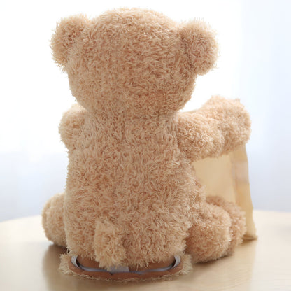 Rückansicht des flauschigen beigen Plüschbären, der mit ausgestrecktem Arm das Tuch hält; am Boden ist die Unterseite zu sehen. 4
