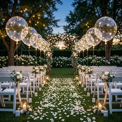 Leuchtende Ballons säumen den Gang einer Gartenhochzeit mit Blumenbogen, weißen Stühlen und Rosenblättern 6