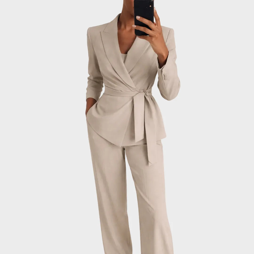 Dasselbe Set in Beige, getragen von einer Frau beim Spiegelselfie, Blazer mit Revers und seitlich gebundenem Gürtel über weiter Hose. 2