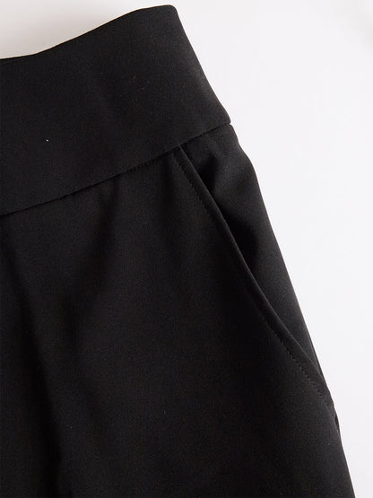 Detailaufnahme der schwarzen Hose mit breitem Bund und eingearbeiteter Seitentasche, flach auf hellem Hintergrund. 5